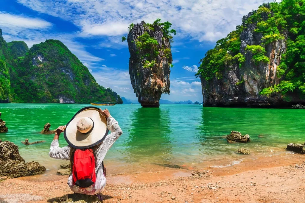 A visitor with a hat looking at James Bond island in Phuket, Thailand, one of the top destinations featured in this Asia travel guide.