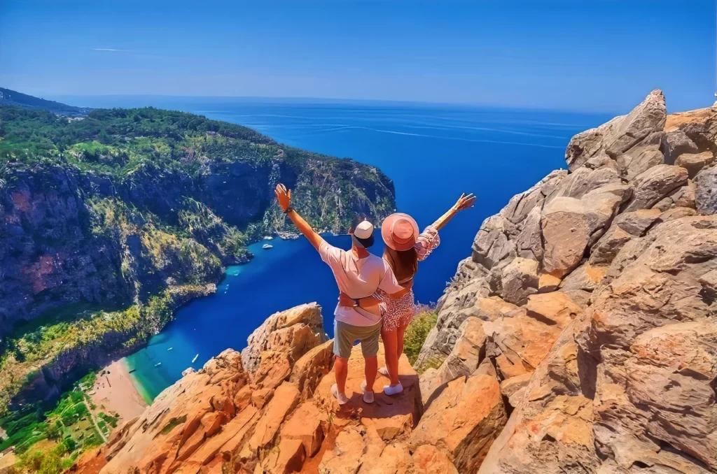 A couple stand together on hill rock overlooking the Blue Lagoon in the Turquoise Coast, one of the top wedding and honeymoon destinations in Turkey.